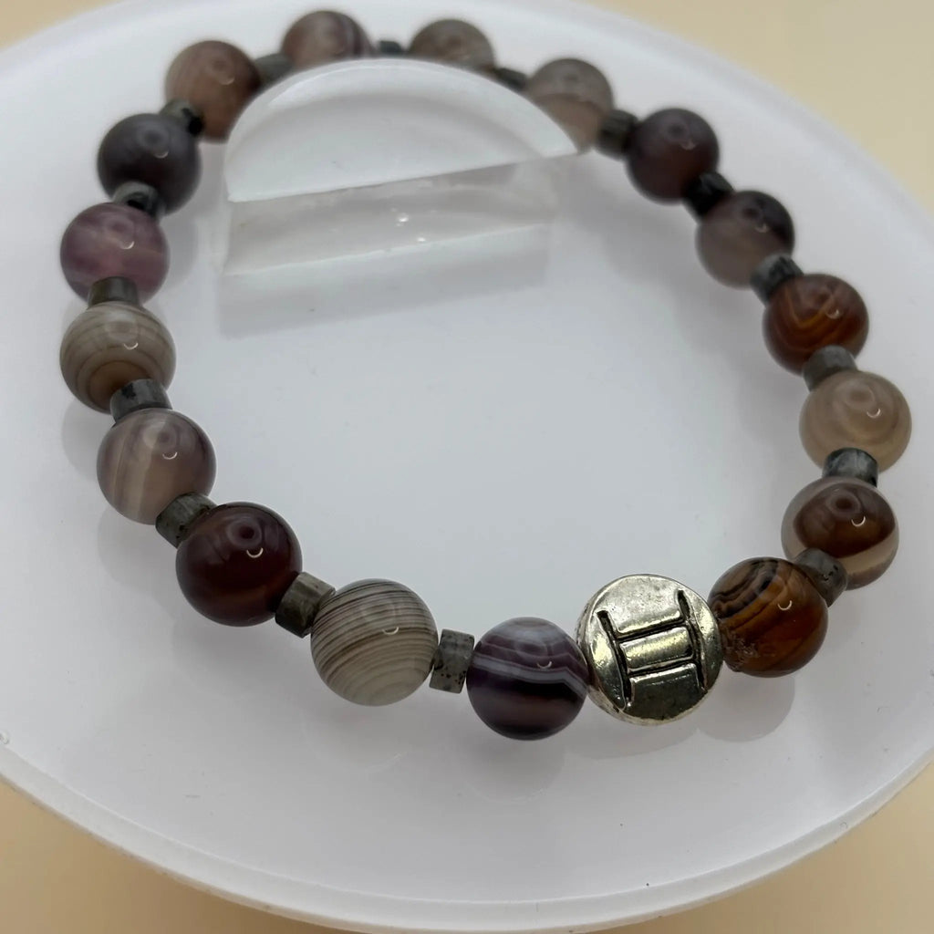 Bracelet en perles brunes et grises, décoré d’une pastille argentée gravée au centre