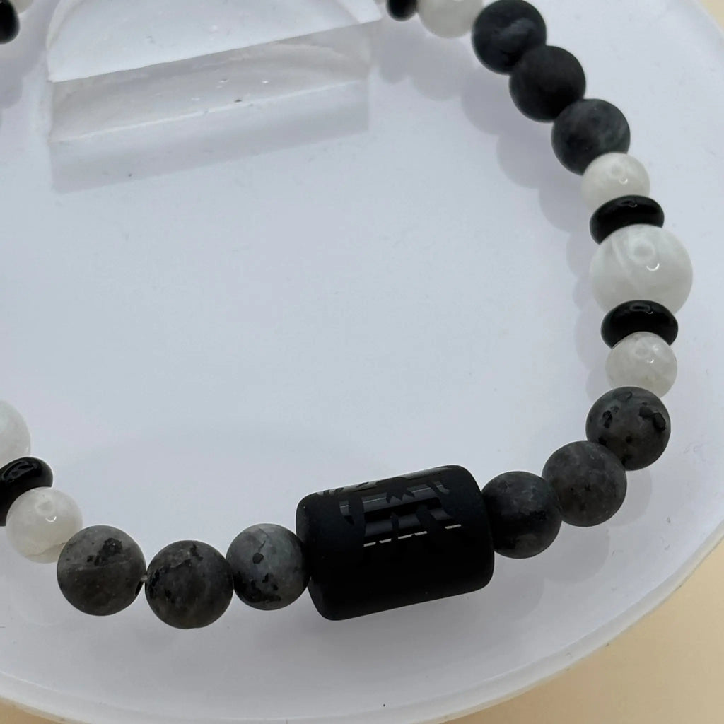 Bracelet en perles bleues, blanches et noires, orné d’une perle cylindrique noire gravé