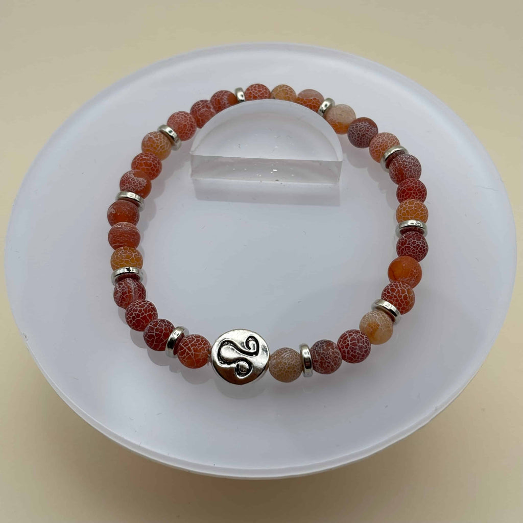 Un bracelet en perles sur élastique avec perles en porcelaine et en verre et médaillon avec le signe du lion