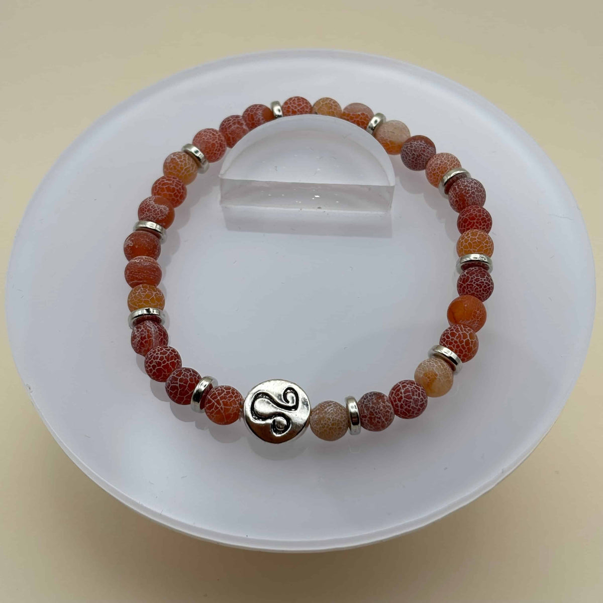 Un bracelet en perles sur élastique avec perles en porcelaine et en verre et médaillon avec le signe du lion