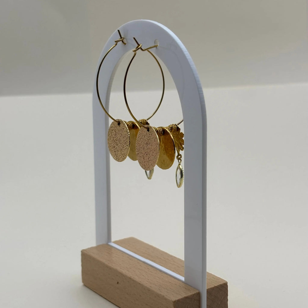 Des boucles d'oreilles créoles  dorées avec pendentif pastille dorée avec une fleur marguerite et des perles