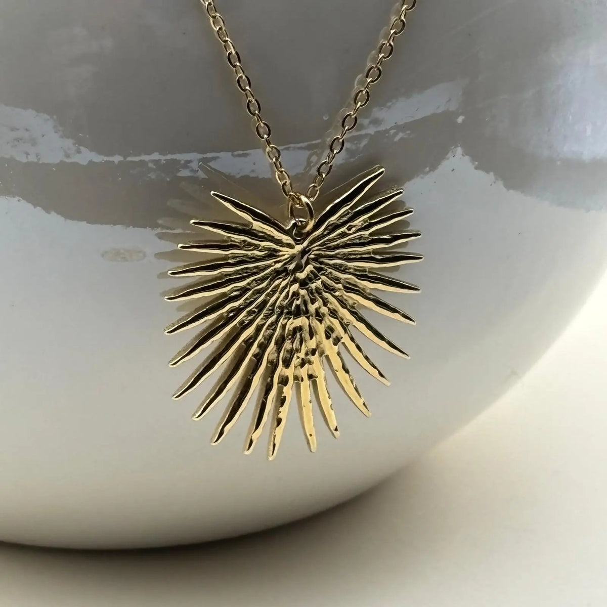 Collier et boucles d'oreilles de couleur dorée avec motif soleil éclatant