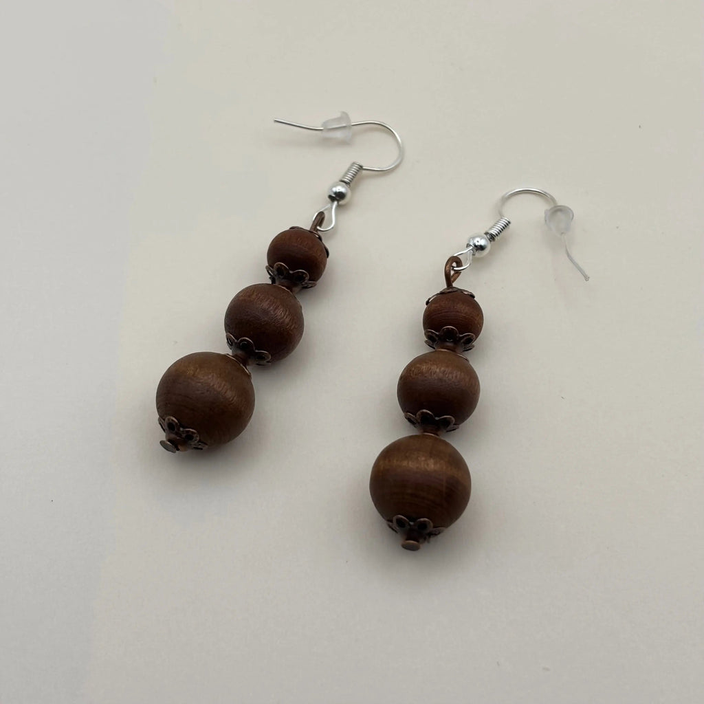 Des boucles d'oreilles artisanales avec fixation argentées et trois perles marron