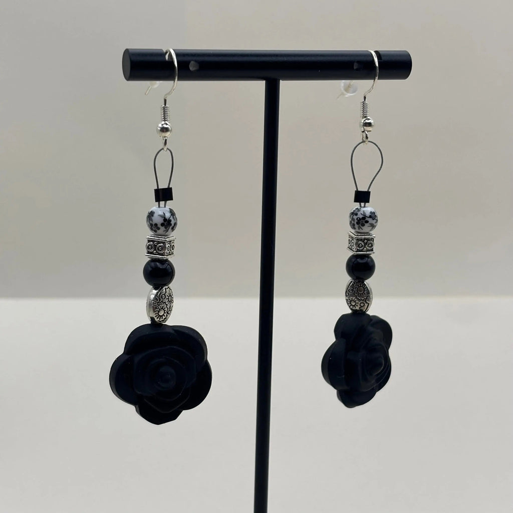 Boucles d'oreilles artisanales avec fixation argentée un breloque en forme de fleur noire et différentes perles 