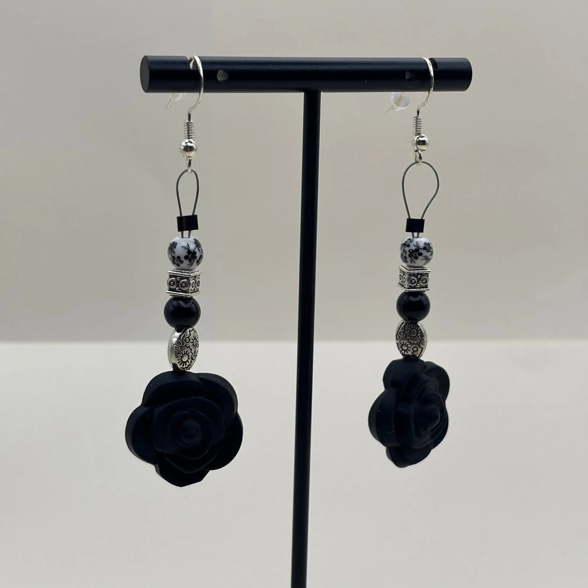 Boucles d'oreilles artisanales avec fixation argentée un breloque en forme de fleur noire et différentes perles 