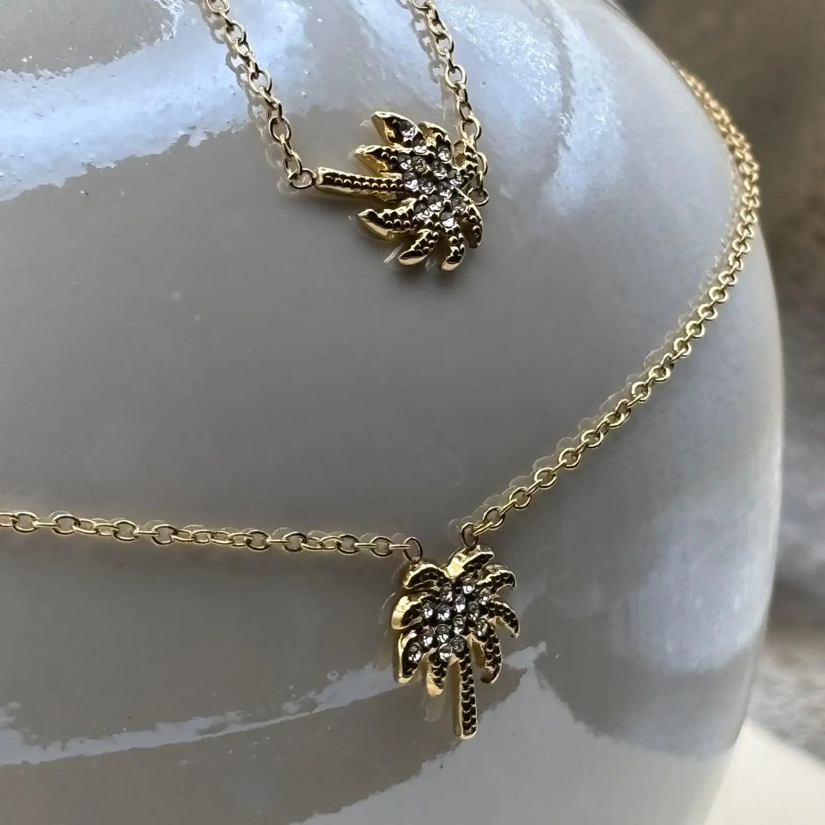 Collier couleur dorée et bracelet à petits maillons avec une breloque en forme de palmier avec des strass 