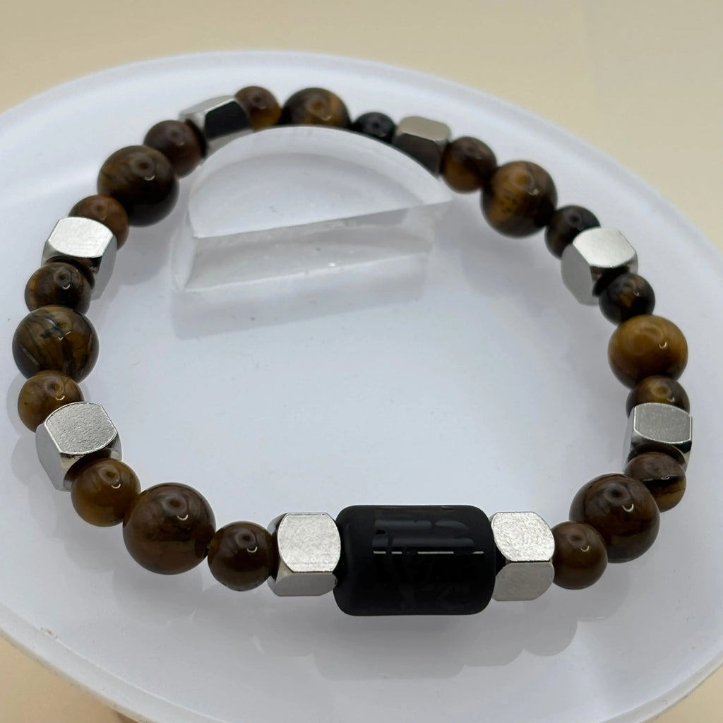 Gros plan sur un bracelet gris, blanc et noir montrant une perle centrale noire gravée