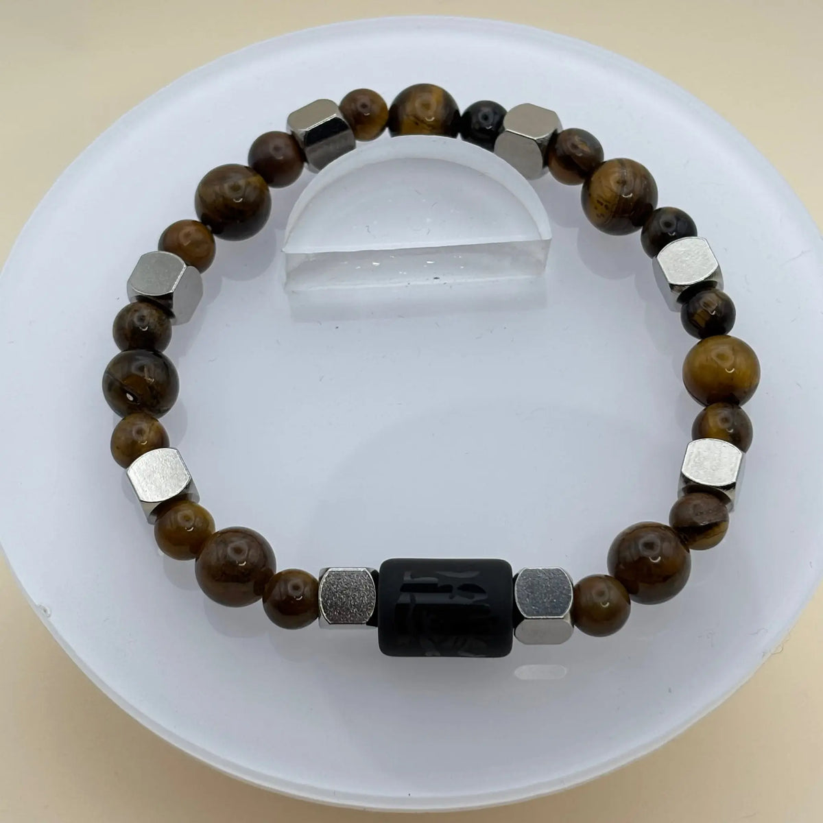 Bracelet en perles grises, blanches et noires, avec un élément central cylindrique noir gravé