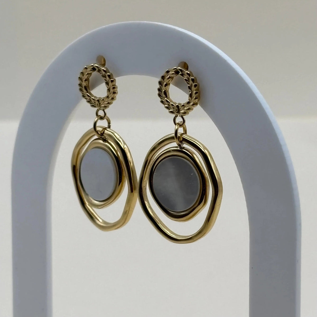 Des boucles d'oreilles dorées avec cercle ciselé doré et double cercle une perle de nacre c'est un bijou en acier inoxydable