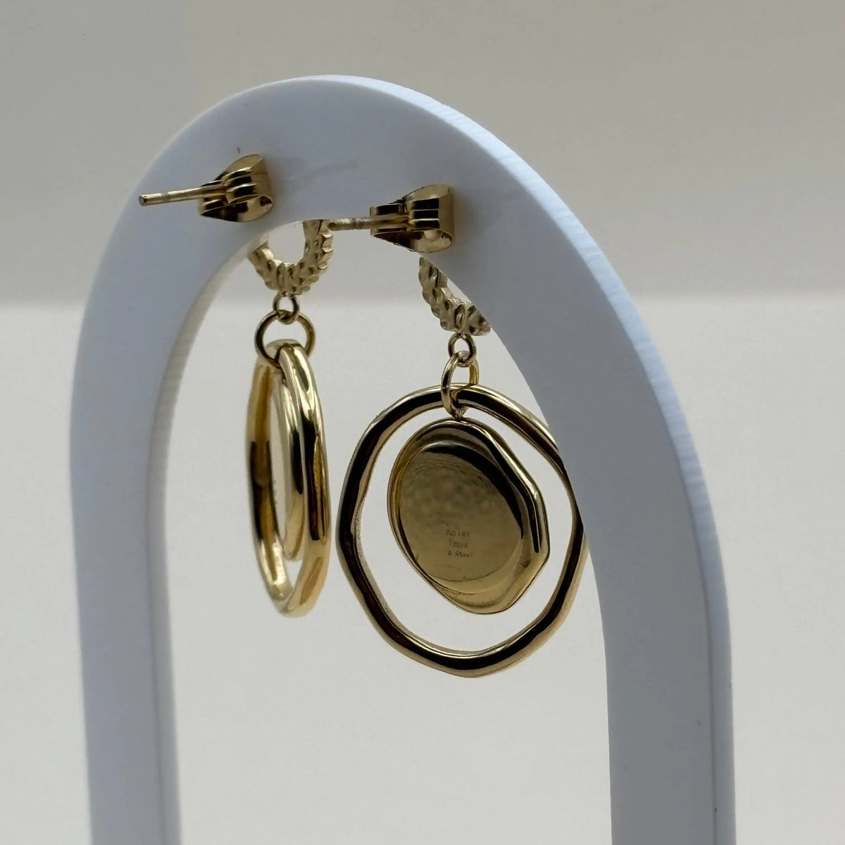 Une paire de boucles d'oreilles dorées avec cercle ciselé doré et double cercle une perle de nacre c'est un bijou en acier inoxydable