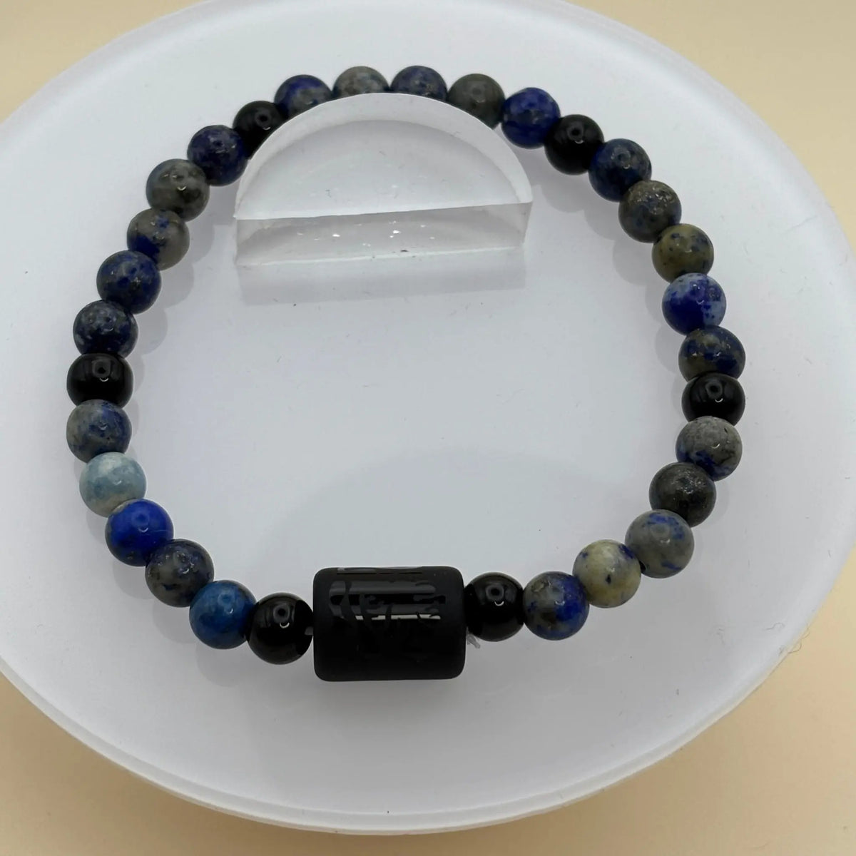 Bracelet combinant tons bleus, gris et blancs, décoré d’une perle centrale noire gravée