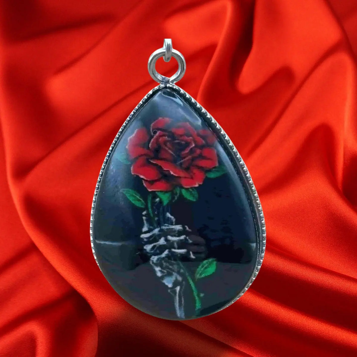 oucles d'oreilles pendentif pour halloween en forme de goutte noire avec à l'intérieur une rose rouge et une main squelette vendues sur le site pretes a briller