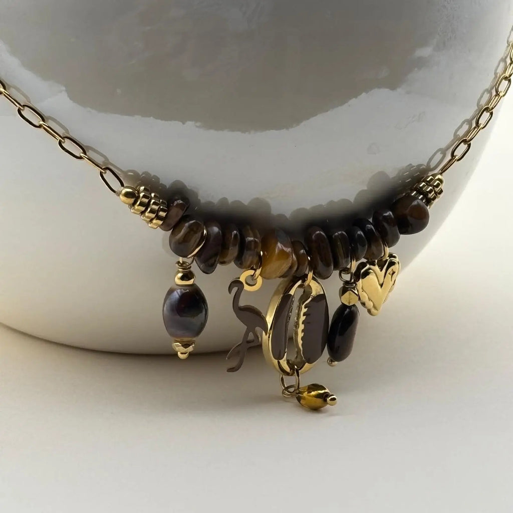 Un collier fantaisie avec une chaine dorée et des breloques cœur flamant noir coquillages et perles noires bijou en acier inoxydable