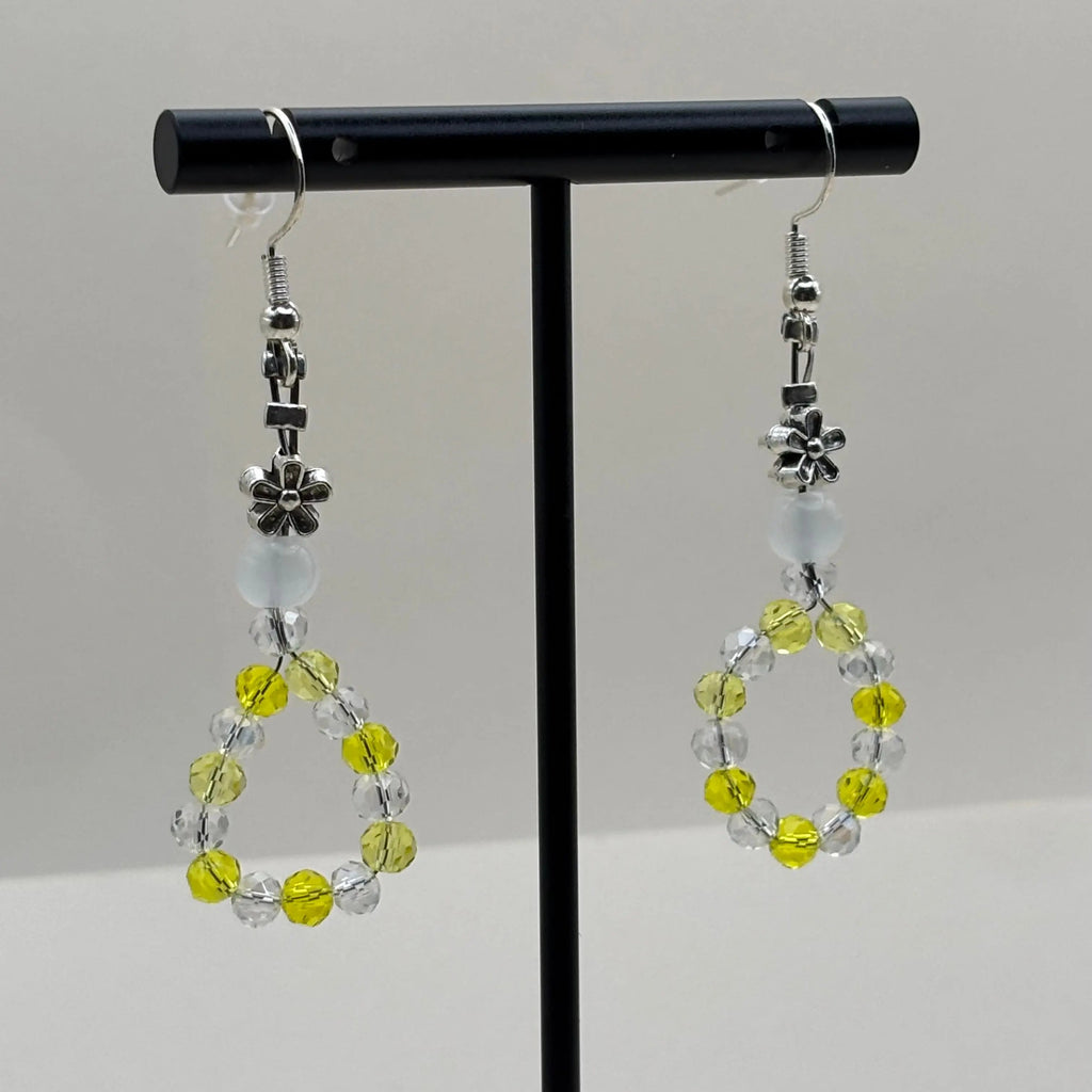 Des boucles d'oreilles pendentif avec des perles acryliques blanches et une couronne en perles jaune et blanches