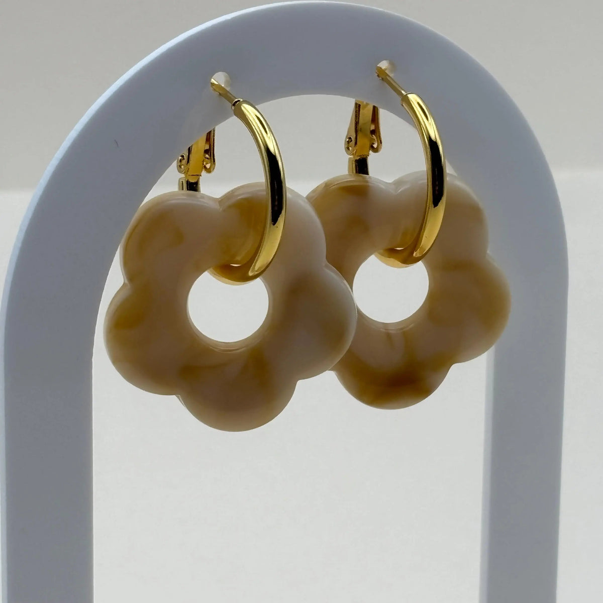 Des boucles d'oreilles dorées façon créoles avec une fleur écrue