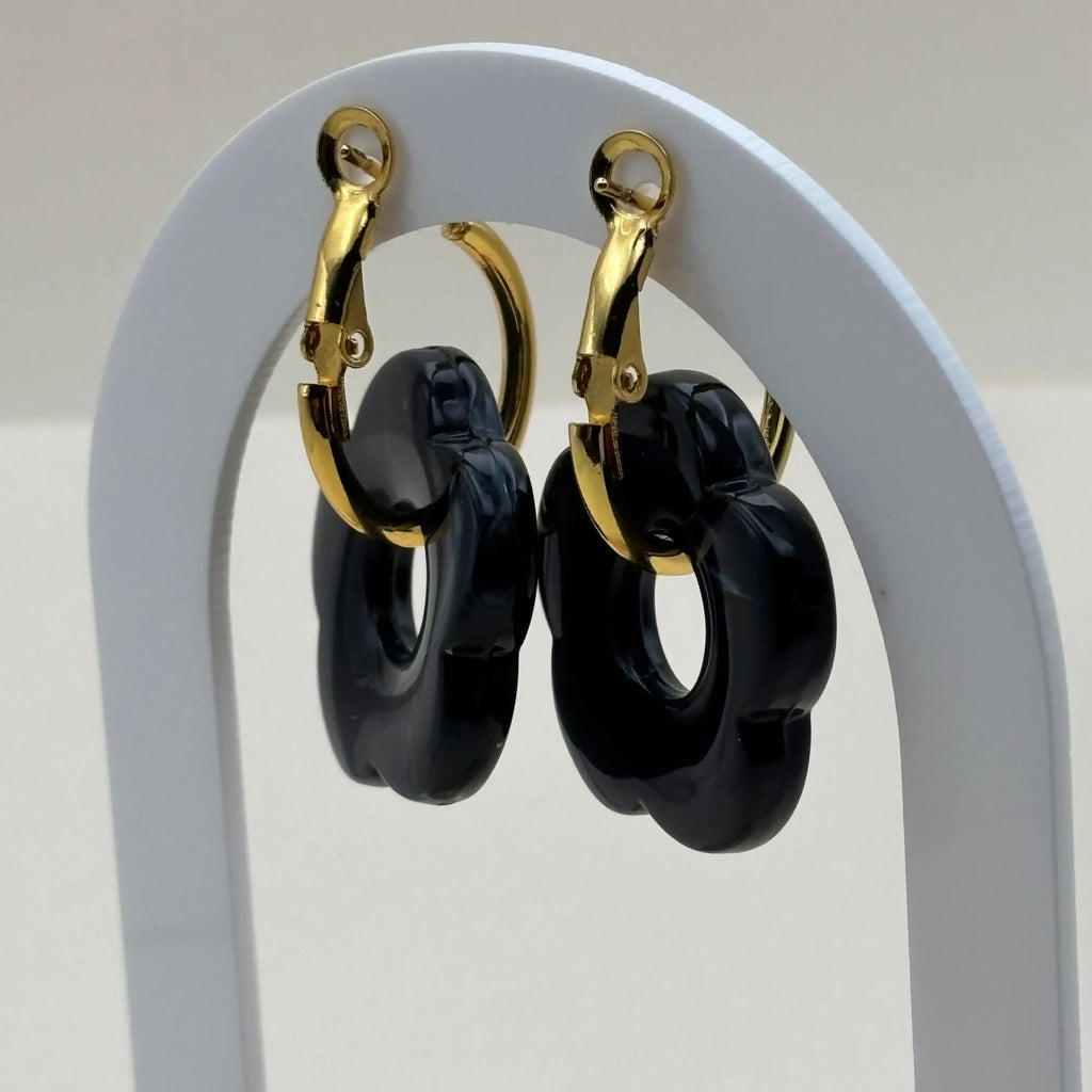 Des boucles d'oreilles dorées façon créoles avec une fleur noire