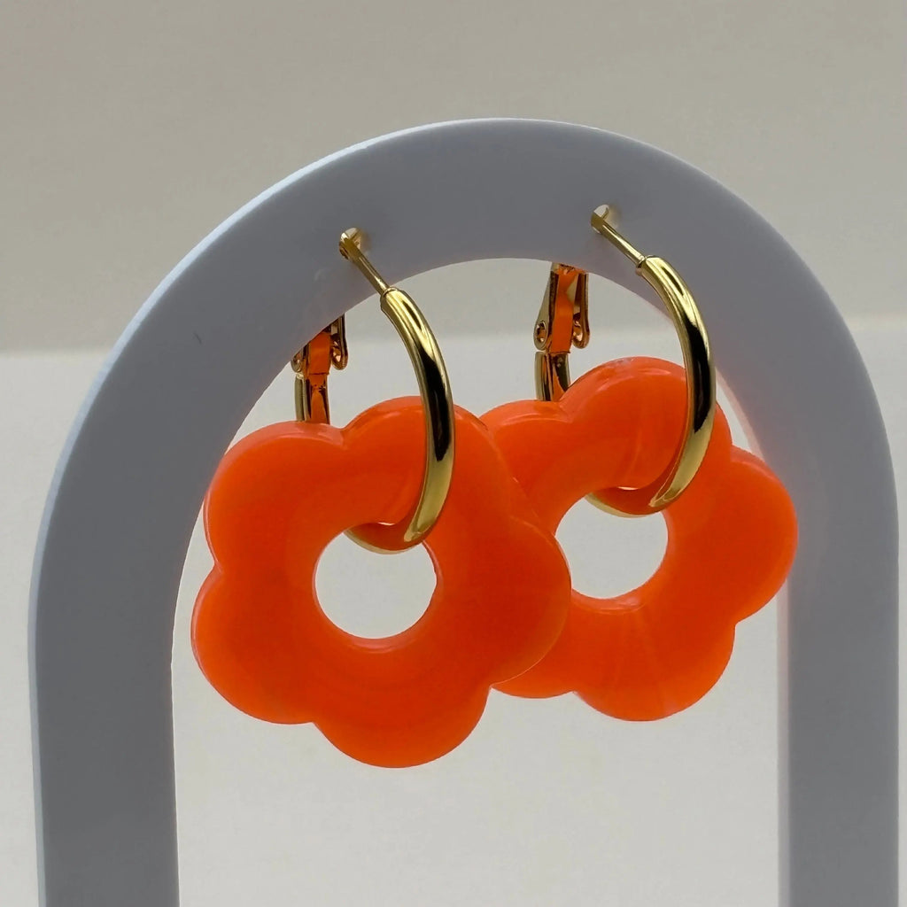 Des boucles d'oreilles dorées façon créoles avec une fleur orange