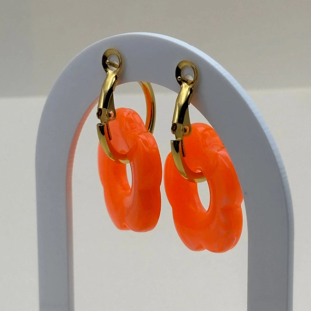 Une paire de boucles d'oreilles dorées façon créoles avec une fleur orange