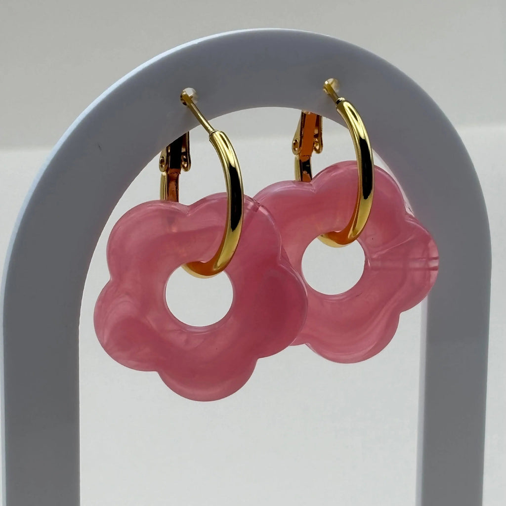 Des boucles d'oreilles dorées façon créoles avec une fleur rose