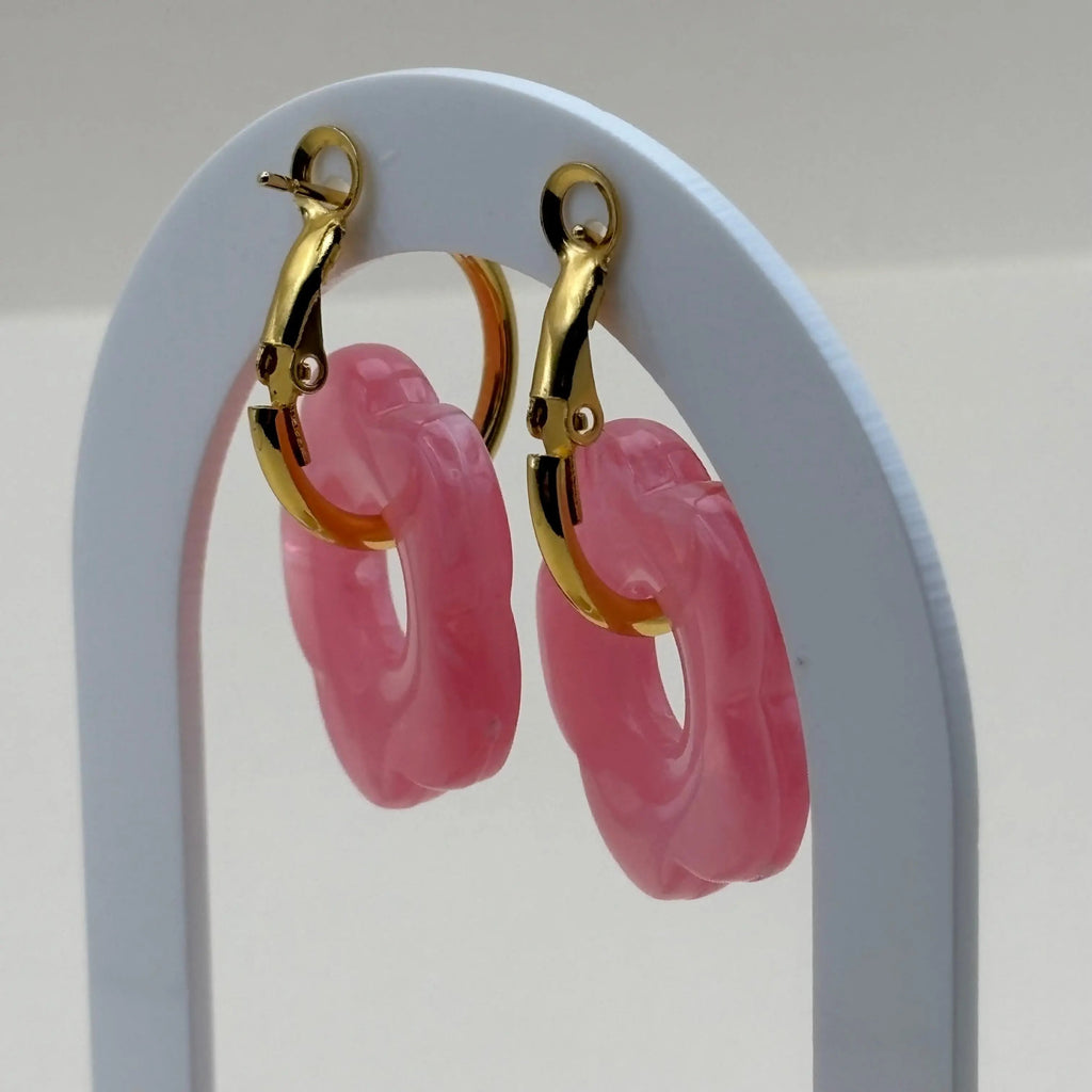 Une paire de boucles d'oreilles dorées façon créoles avec une fleur rose