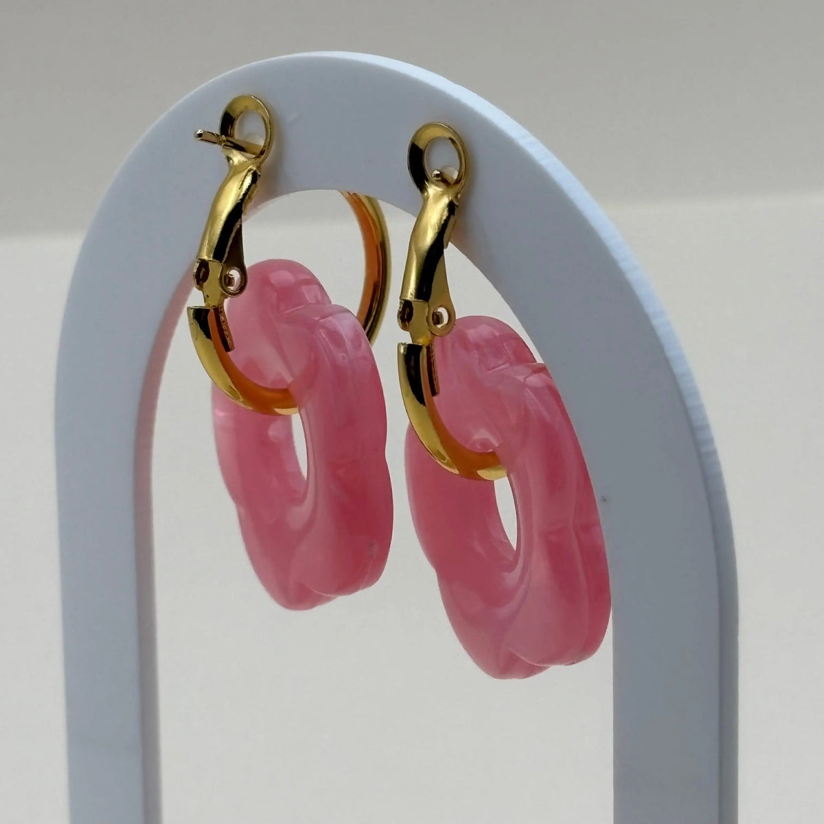 Une paire de boucles d'oreilles dorées façon créoles avec une fleur rose