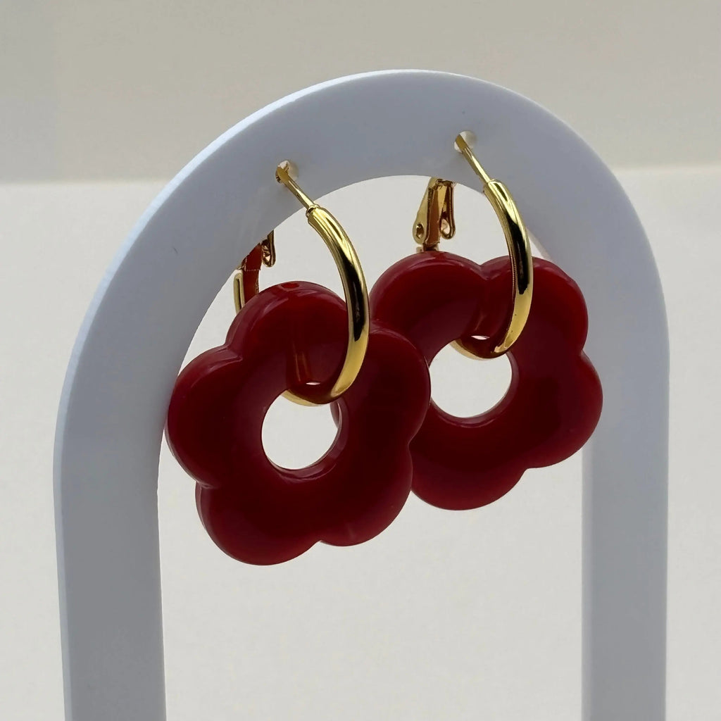 Des boucles d'oreilles dorées façon créoles avec une fleur rouge