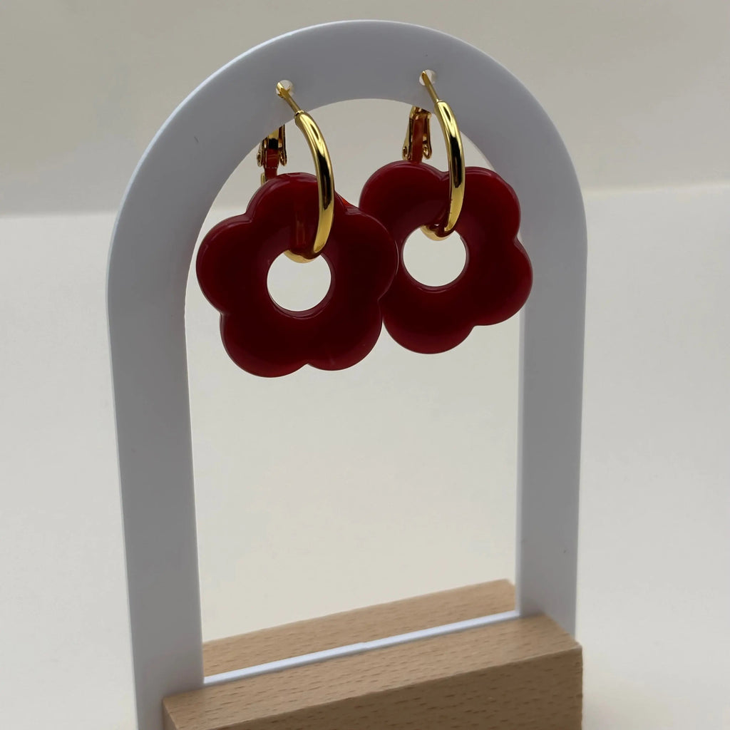 Une paire de boucles d'oreilles dorées façon créoles avec une fleur rouge