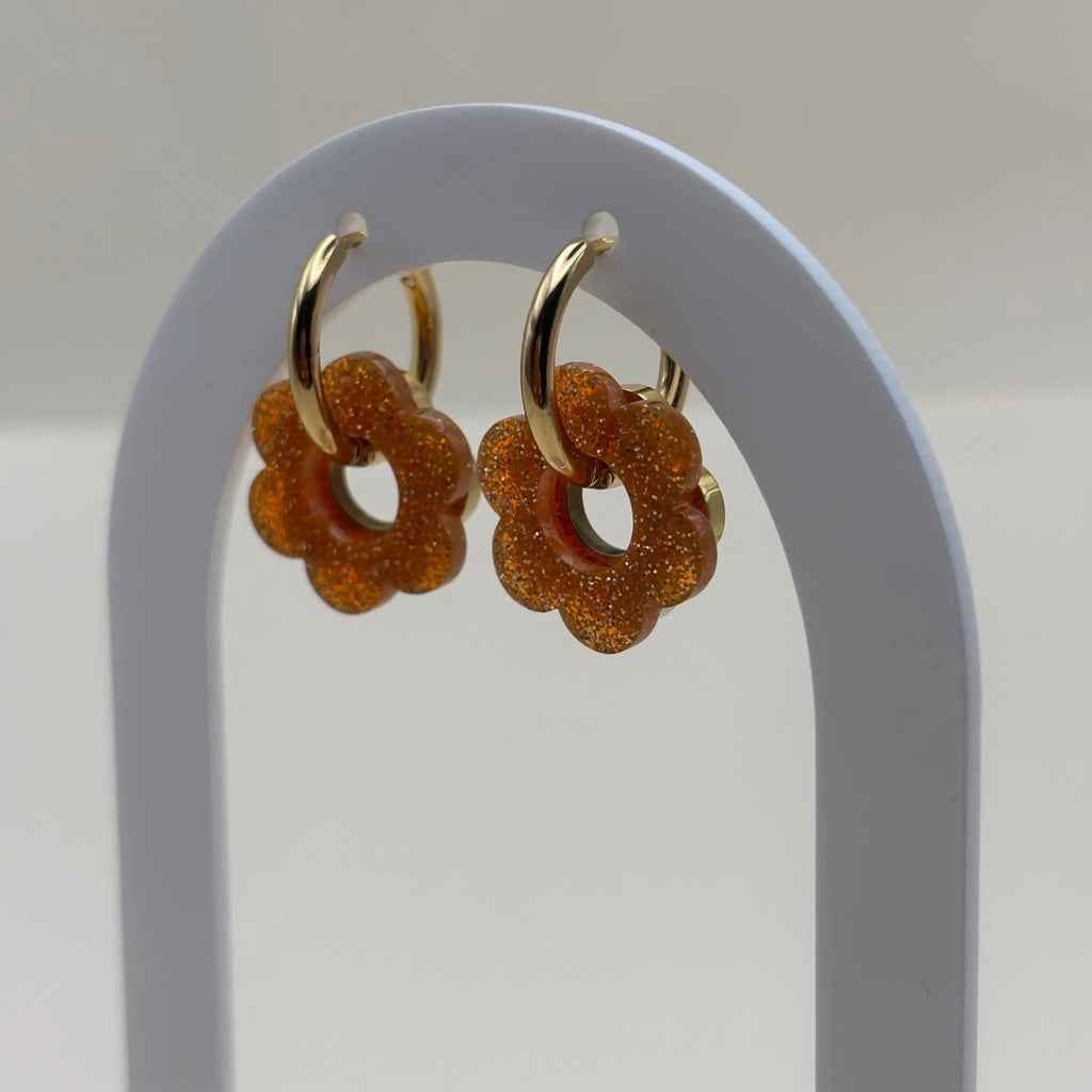 Des boucles d'oreilles dorée façon créole avec une fleur orange et une fleur dorée