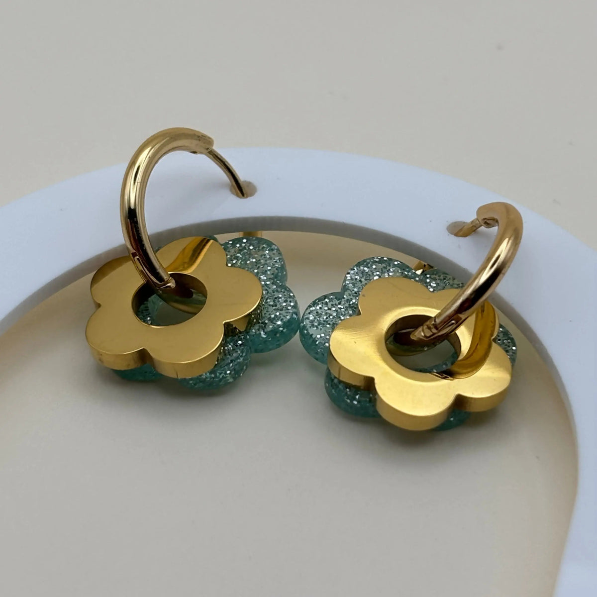 Des boucles d'oreilles dorée façon créole avec une fleur bleue vert et une fleur dorée