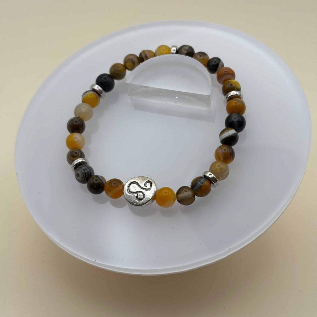 Un bracelet en perles sur élastique avec perles en porcelaine et en verre et médaillon avec le signe zodiacal du lion
