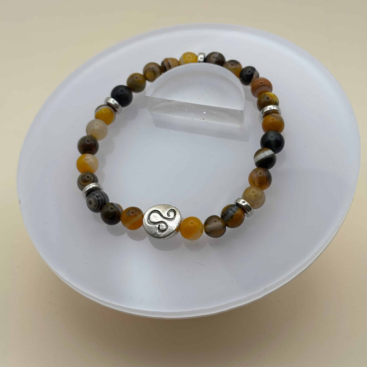 Un bracelet en perles sur élastique avec perles en porcelaine et en verre et médaillon avec le signe zodiacal du lion