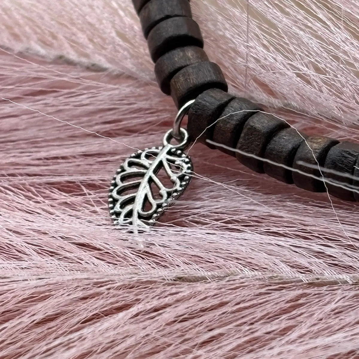 Vue de près d'un bracelet en perles artisanal avec breloques cœurs et perles plates en bois sur élastique