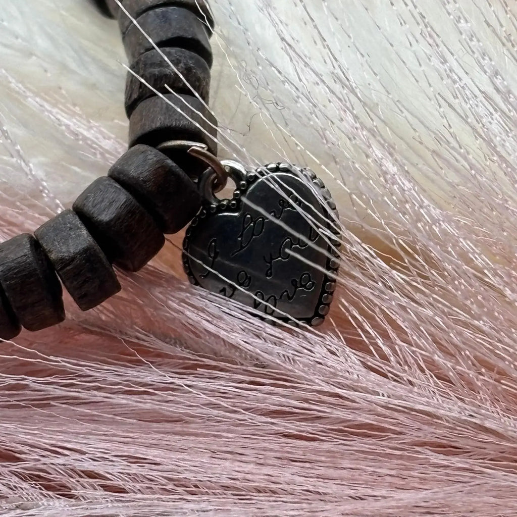 Vue de détail d'un bracelet en perles artisanal avec breloques cœurs et perles plates en bois sur élastique