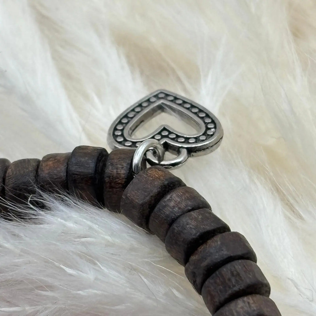 Vue détail d'un bracelet en perles artisanal avec breloques cœurs et perles plates en bois sur élastique