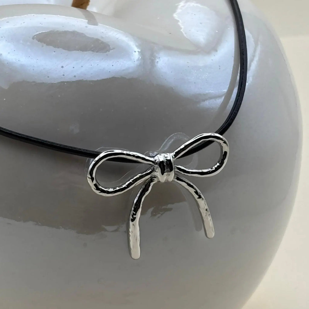 Collier argenté pendentif motif nœud argenté sur un lien en cuir noir