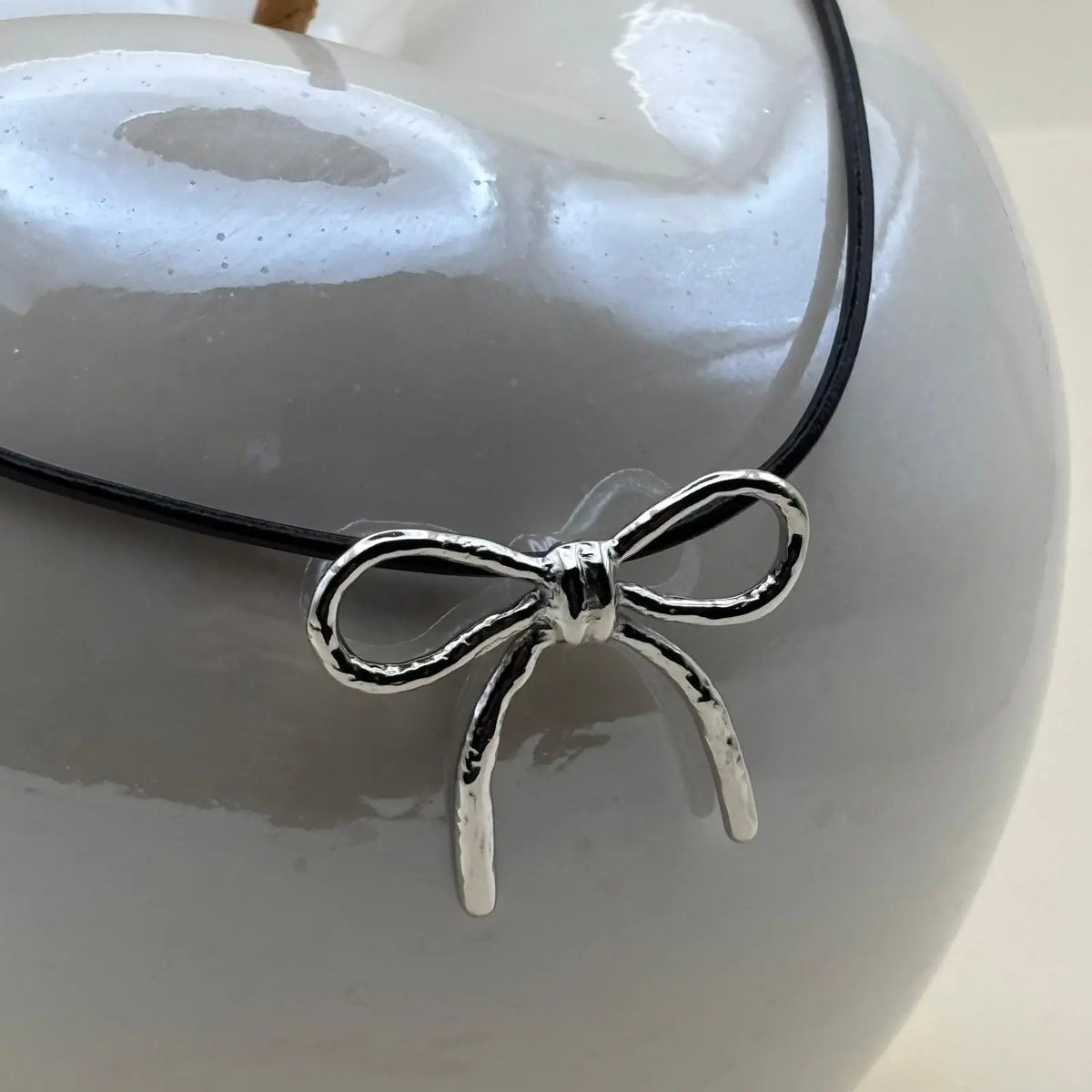 Collier argenté pendentif motif nœud argenté sur un lien en cuir noir