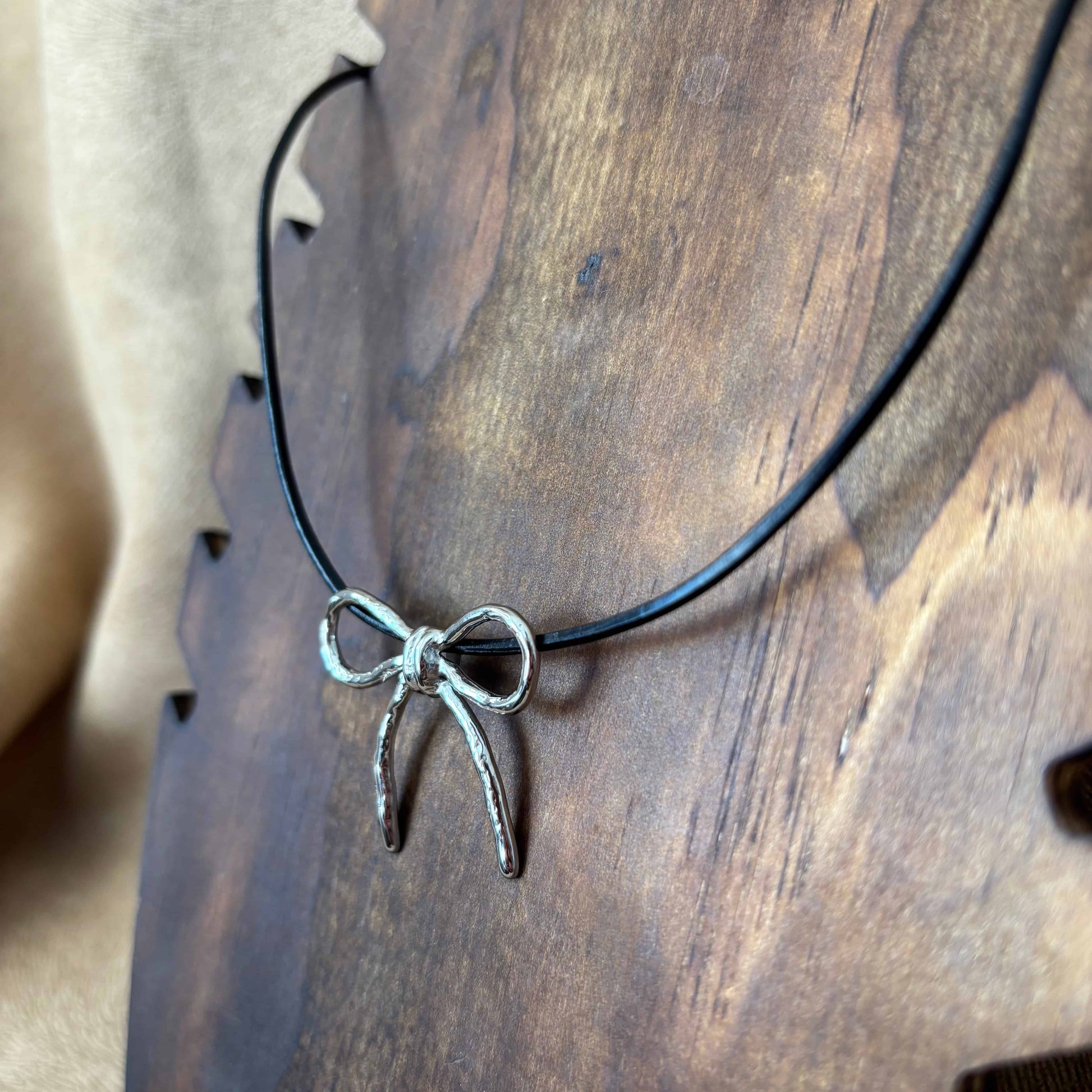 Collier argenté |Pendentif nœud argenté vue de près | Sur lien en cuir noir |Acier inoxydable
