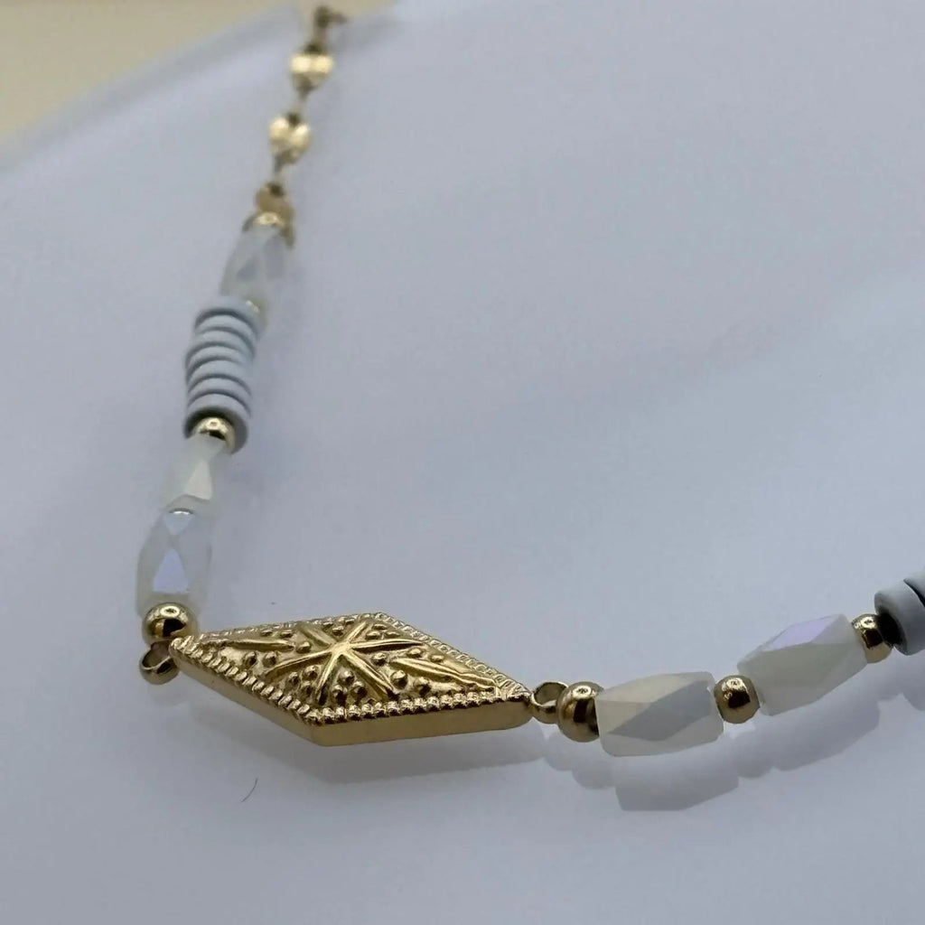 Bracelet fantaisie avec  de petits maillons dorés avec une breloque rose des vents en forme de losange