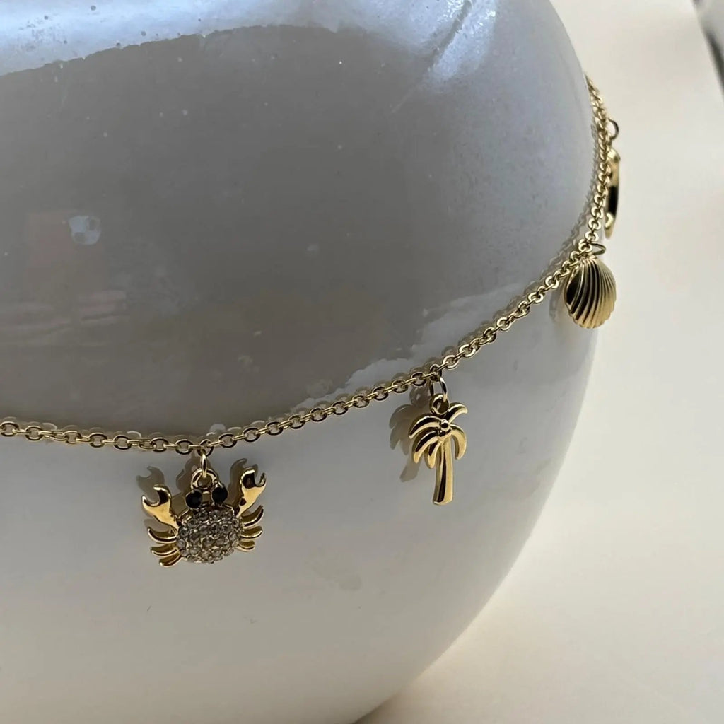 Un collier doré avec breloques coquillage palmier crabe étoile de mer et baleine en acier inoxydable