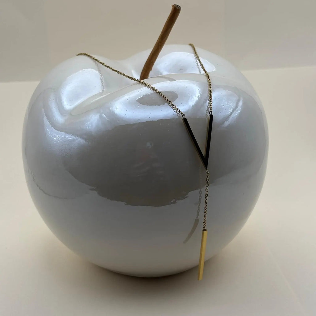 Un collier doré avec motif V en doré et médaillon allongé