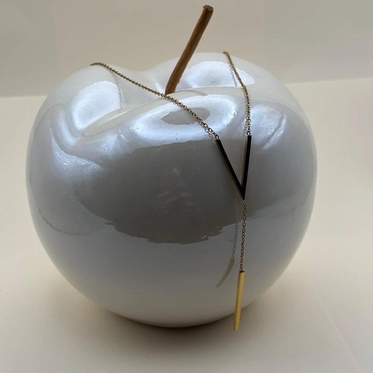 Un collier doré avec motif V en doré et médaillon allongé