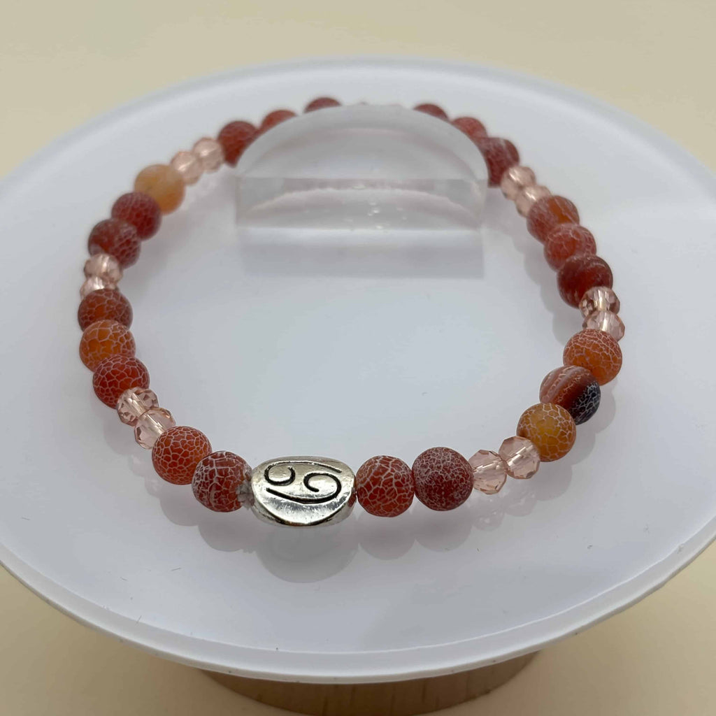Un beau bracelet en perles sur élastique avec perles en porcelaine et en verre et médaillon avec le signe zodiaque du cancer