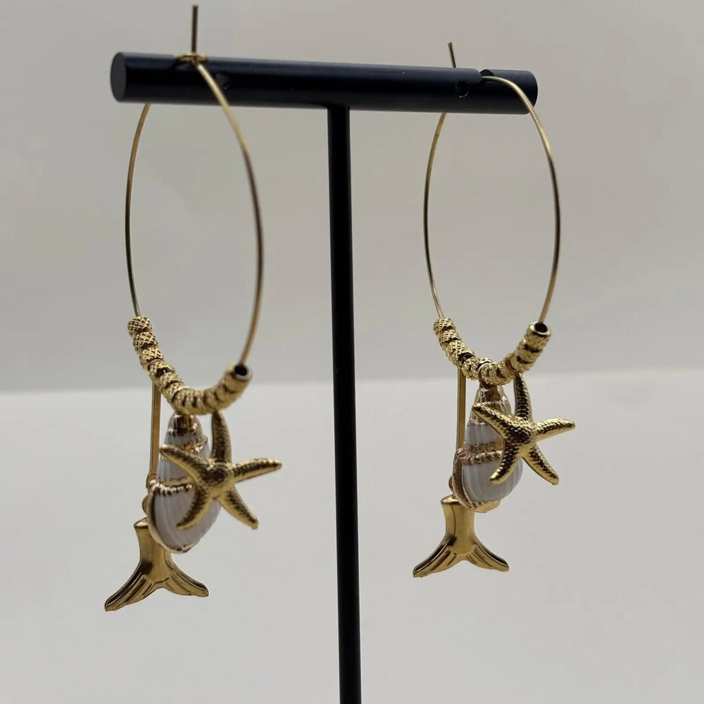 Des boucles d'oreilles créoles dorées avec breloques coquillage queue de baleine et étoile de mer