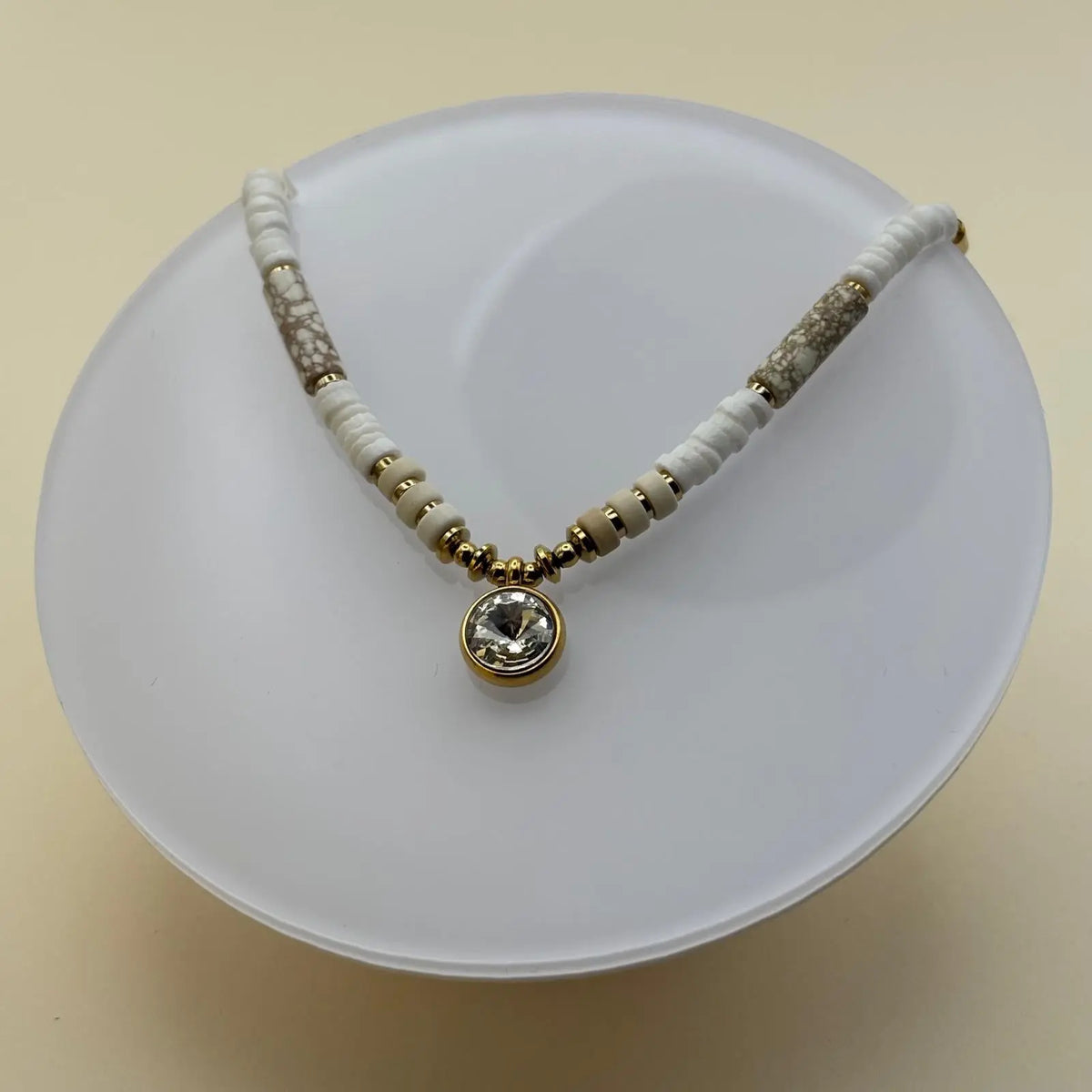 Bracelet doré avec perles plates blanches marbrées et beiges avec médaillon brillant