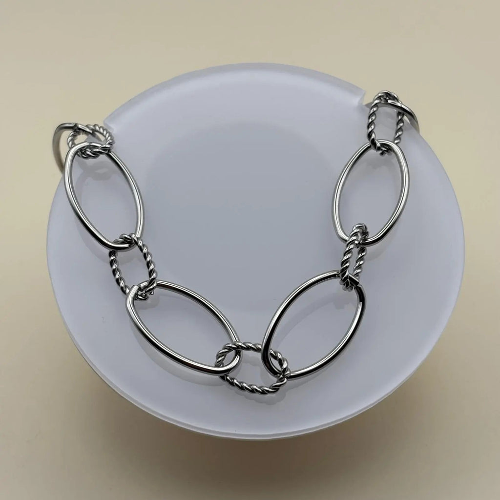 Un collier argenté avec anneaux ovales lisses et torsades en acier inoxydable