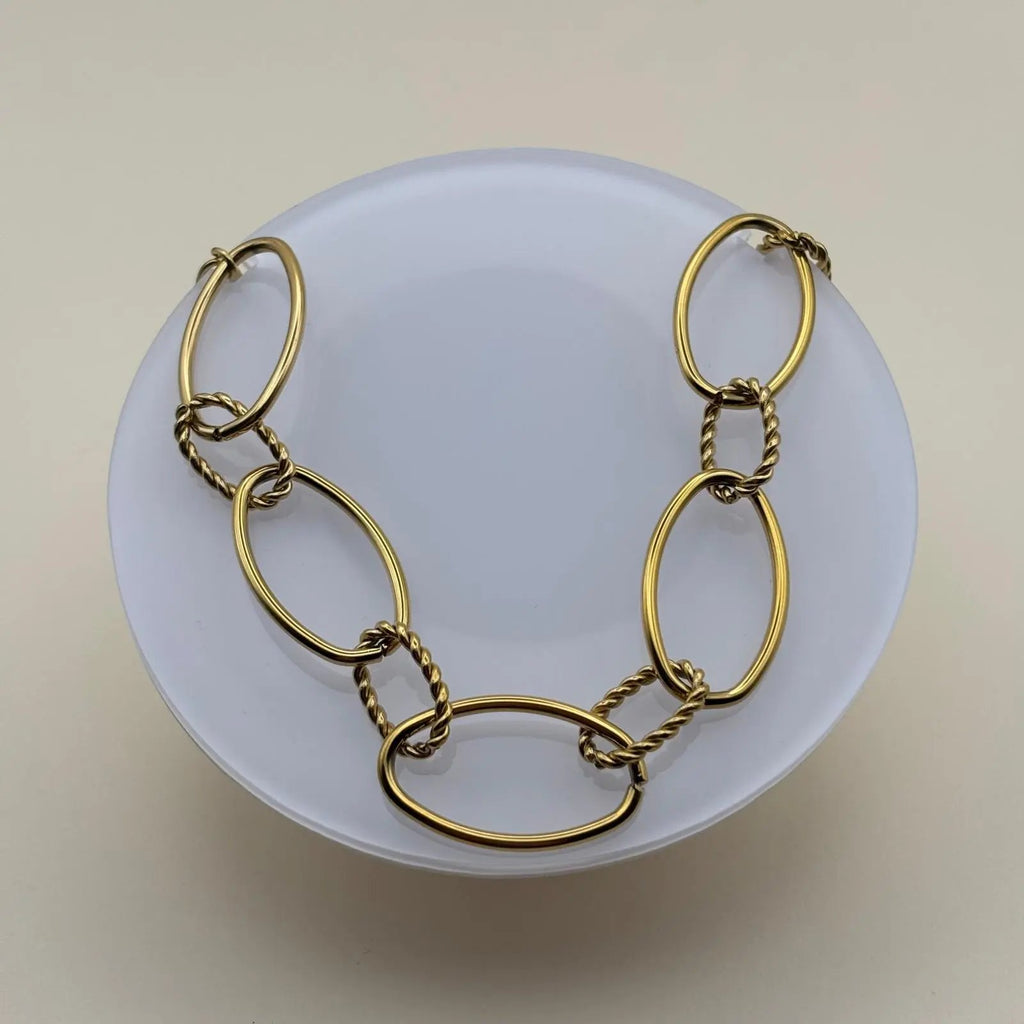 Un collier doré avec anneaux ovales lisses et torsades en acier inoxydable