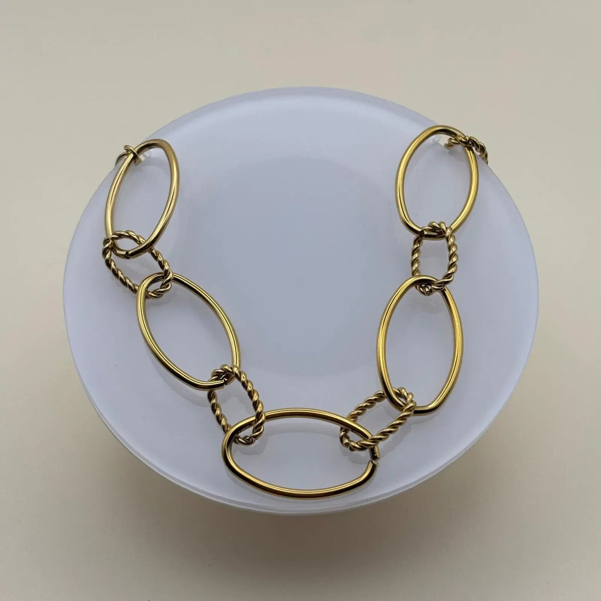Un collier doré avec anneaux ovales lisses et torsades en acier inoxydable