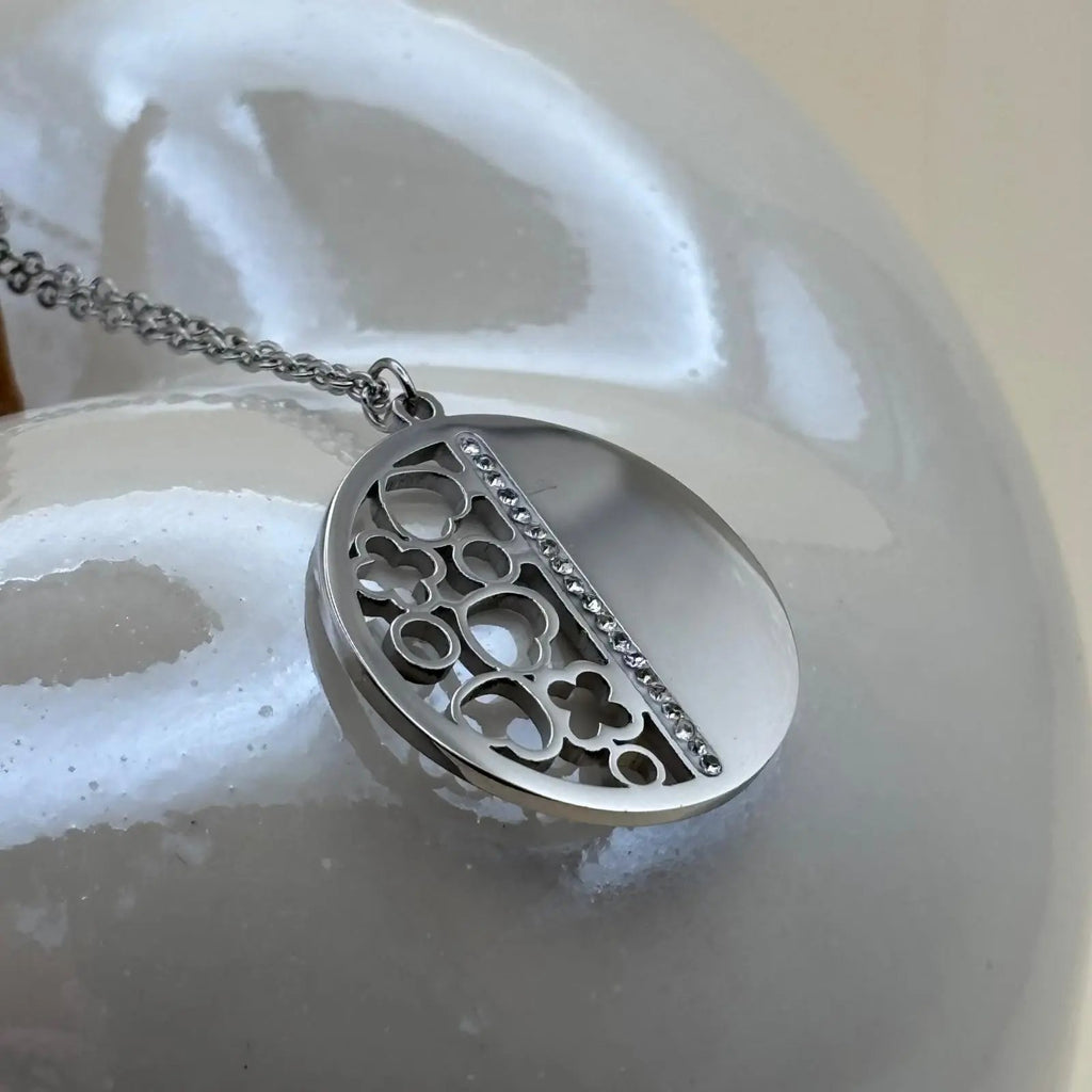 Un collier argenté avec médaillon demie sphère pleine et demie sphère cœurs trèfle  en acier inoxydable 