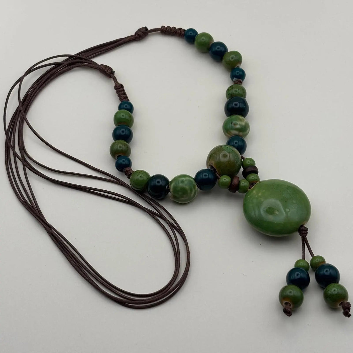 Collier fantaisie ethnique avec lien en nylon marron réglable avec perles céramique et médaillon couleur verte