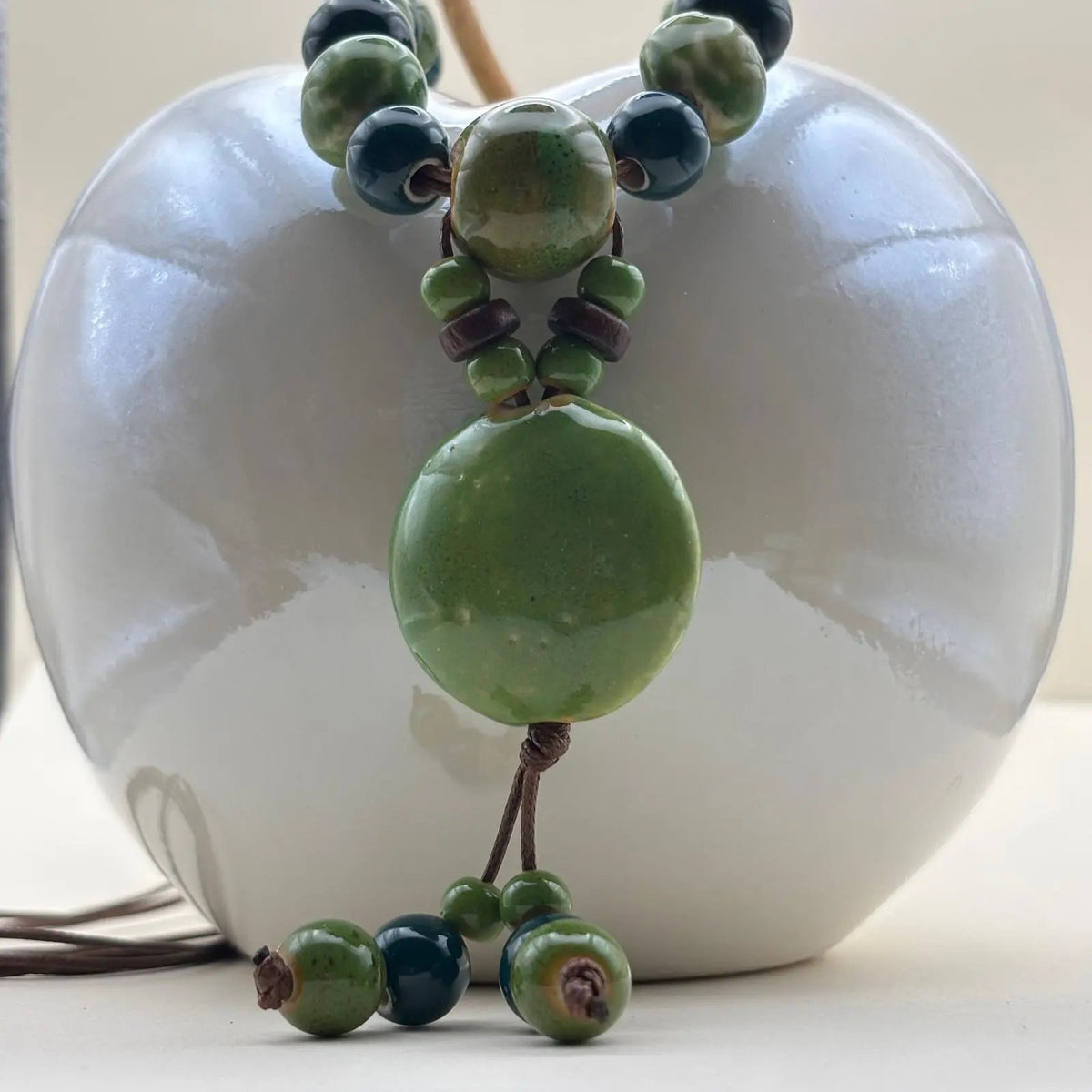 Un collier fantaisie ethnique avec lien en nylon marron réglable avec perles céramique et médaillon couleur verte